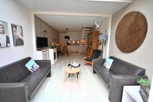a living room with two leather couches and a table at Woeste Hoeve 114 in Biggekerke