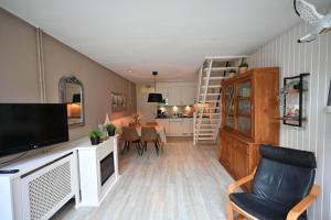 a living room with a television and a dining room at Woeste Hoeve 114 in Biggekerke