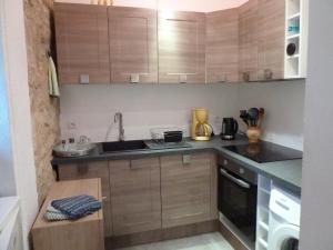 eine Küche mit Holzschränken und einem Waschbecken in der Unterkunft Appartement centre médiéval - Le Cosy de Sarlat in Sarlat-la-Canéda