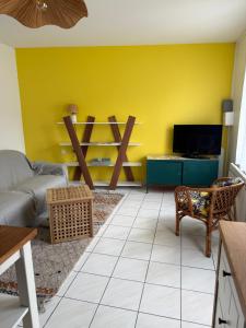 a living room with a couch and a yellow wall at La Tranche Cozy Stay! in La Tranche-sur-Mer