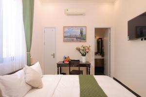 a bedroom with a bed and a table with flowers at APT Hotel Phan Rang in Phan Rang–Tháp Chàm