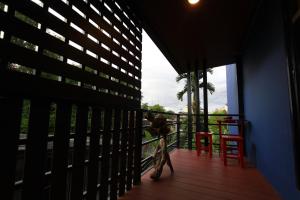 een vrouw die op een balkon staat en uit een raam kijkt bij Chez Pom in Chiang Mai