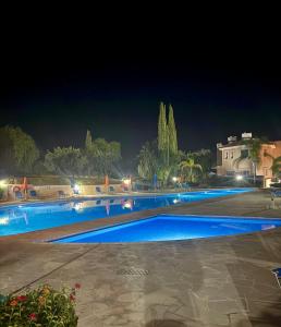 a large swimming pool with blue water at night at Polis Gardens Pool Apartment in Polis Chrysochous