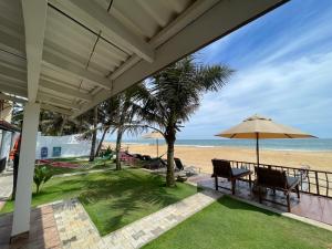 a porch with a bench and an umbrella on the beach at Saman Beach Guest House in Galle