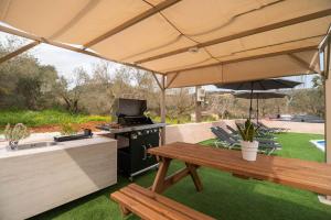 an outdoor kitchen with a picnic table and an umbrella at Villa Pasiphae by PosarelliVillas in Vamos