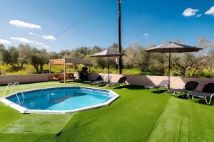 a swimming pool on a lawn with chairs and umbrellas at Villa Pasiphae by PosarelliVillas in Vamos