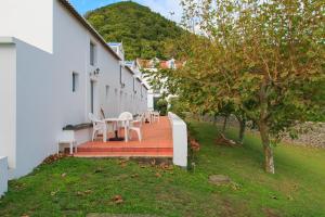 eine Terrasse mit einem Tisch und Stühlen neben einem Gebäude in der Unterkunft Apartamentos da Galé in Caloura