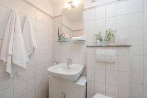 a white bathroom with a sink and a toilet at Dünensand in Süderende +17 photos