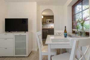 a white dining room with a white table and a television at Dünensand in Süderende