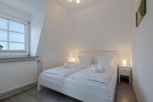 a white bed in a room with a window at Meeresbrandung in Süderende