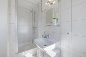 a white bathroom with a sink and a shower at Meeresbrandung in Süderende +17 photos