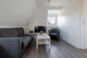 a living room with a couch and a table and a chair at Sonnenaufgang in Süderende