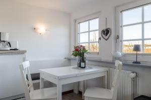 a white kitchen with a white table and chairs at Sonnenaufgang in Süderende