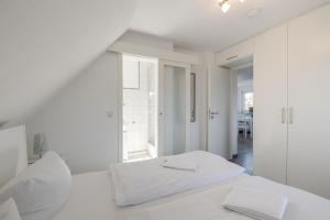 a white bedroom with a bed and a window at Sonnenaufgang in Süderende