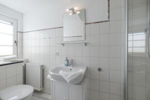a white bathroom with a sink and a toilet at Sonnenaufgang in Süderende +14 photos