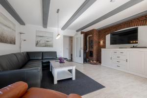 a living room with a black leather couch and a table at Robbennest in Süderende