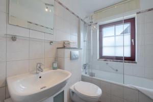 a white bathroom with a sink and a toilet at Robbennest in Süderende +31 photos