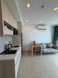 a kitchen and living room with a couch and a table at City Garden Olympus Premier By Vacation Vibes in Pattaya South