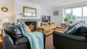 a living room with two leather chairs and a fireplace at Thalassa in Cemaes Bay