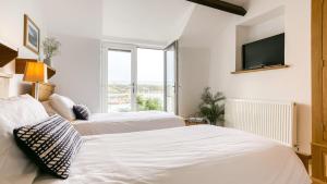 two beds in a room with a tv on the wall at Thalassa in Cemaes Bay