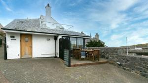 a white building with a table and a stone wall at Thalassa in Cemaes Bay