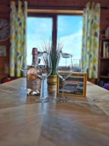 three wine glasses sitting on a table with a bottle of wine at 3-Bed Ocean View Lodge - Parking & Terrace in Ilfracombe
