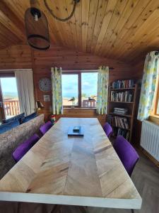 a large wooden table in a living room with purple chairs at 3-Bed Ocean View Lodge - Parking & Terrace in Ilfracombe