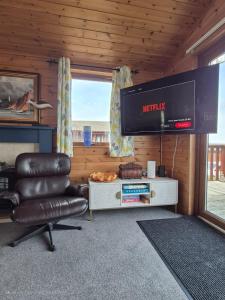 a living room with a television and a leather chair at 3-Bed Ocean View Lodge - Parking & Terrace in Ilfracombe +34 photos
