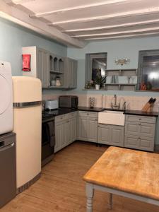 a kitchen with white cabinets and a sink and a table at Fossewold Cotswold Barn in Chipping Campden