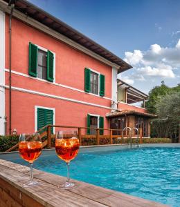 two glasses of wine sitting on a table next to a swimming pool at B&B Villa Regina in Pisa