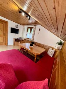 a living room with a red couch and a table at Pferdehof Almgut - Reiten für Kinder, Natur und Erholung nahe Salzburg in Faistenau