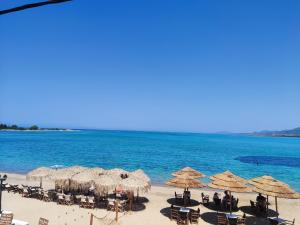 a beach with umbrellas and chairs and the ocean at Almiriki- Ground Floor Seafront Studio in Elafonisos
