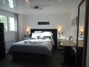 a bedroom with a large bed with white sheets and pillows at Le jardin de Brigitte in Vergeroux