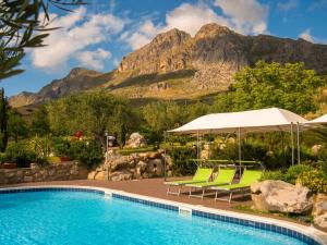 ein Pool mit Stühlen und Sonnenschirm und Berge in der Unterkunft Crapa Licca in Ventimiglia di Sicilia