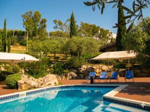 ein Schwimmbecken mit zwei Stühlen und Sonnenschirmen in der Unterkunft Crapa Licca in Ventimiglia di Sicilia
