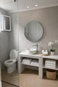 a bathroom with a sink and a toilet and a mirror at Almyra Suites in Archangelos