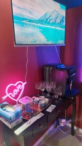 a table with wine glasses and a television on a wall at Love room les pins in Le Muy