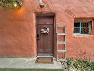 a red building with a brown door and a ladder at Casita Adobe in Grand Junction