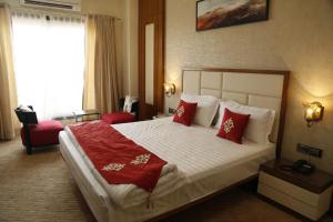 a hotel room with a large bed with red pillows at Hotel Jannat Celebration in Wani +6 photos