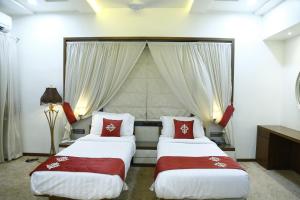 two beds in a hotel room with red pillows at Hotel Jannat Celebration in Wani