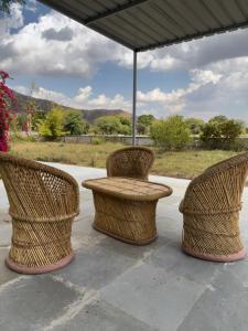 three wicker chairs and a table under an umbrella at The Celestine Villa in Thūr