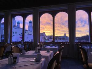 a restaurant with tables and chairs in a room with windows at Hotel Wilder Mann in Passau