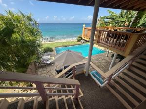 a patio with an umbrella and chairs next to a pool at Birdies Nest Upper 2 Bedroom Beach View in Black Rock