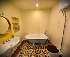 a bathroom with a tub and a toilet and a sink at The Little Hideaway - La Petite Maison Cachée in Noyers