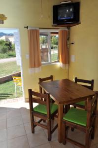 einen Holztisch und Stühle mit einem TV an der Wand in der Unterkunft Cabaña Newen in Capilla del Monte