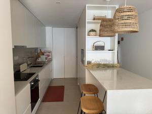 a kitchen with white cabinets and a counter with two stools at Sea Breeze - Espinho Beach in Espinho