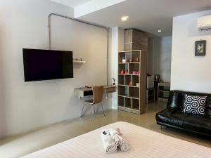 a living room with a black leather couch and a tv at ToffyHome in Phetchabun