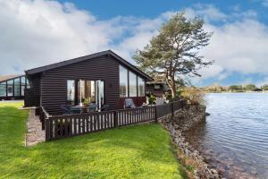 a black house on the shore of a lake at Keer Lodge a lakeshore haven Pine Lake Resort in Carnforth