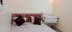 a bed with pillows on top of it in a room at Mukherjee Lodge in Rāmpur Hāt