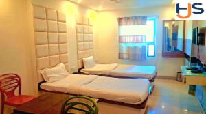 two beds in a room with a table and chairs at Hotel Jyoti Sanjay in Pūrnia